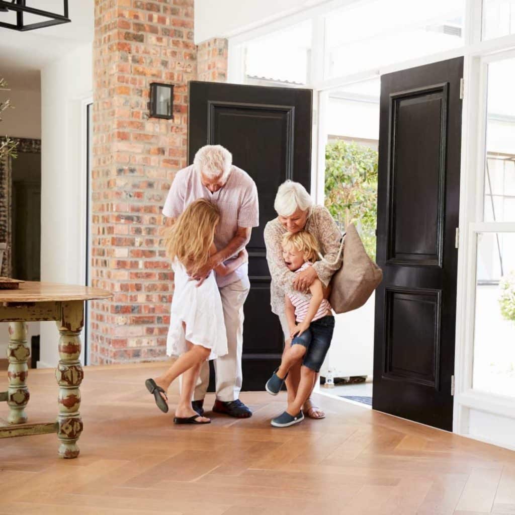 Grandparents entering a home and hugging their grandchildren