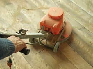 man refinishing hardwood floors with a machine