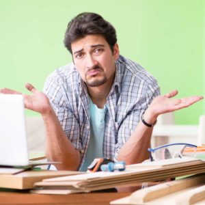 man shrugging looking confused on a table full of wood