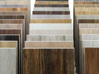 multiple floor plank samples in different shades of hardwood vinyl and laminate
